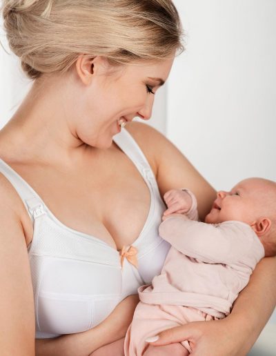 Frau mit Säugling im Arm trägt Still-BH in weiß